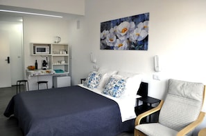 Une chambre d’hôtel avec un lit, un bureau doté d’un micro-ondes, une chaise et un tableau au mur.