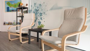 A modern room with two upholstered chairs, a small table, and a decorative wall with a map. - Cozy Seaside Studio Apartment C - Faraway (Lagoa)