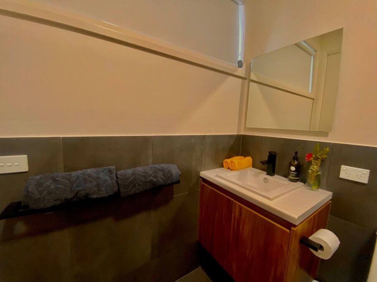 A bathroom with a wooden cabinet, a white sink, a mirror, and a towel rack.