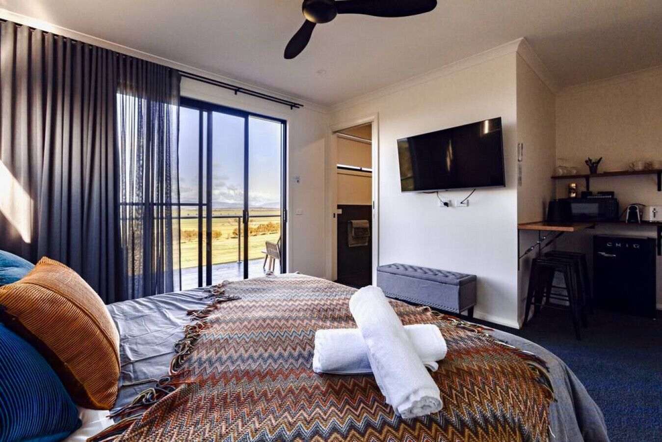 A hotel room with a bed, a desk, a television, and a view of the outdoors.