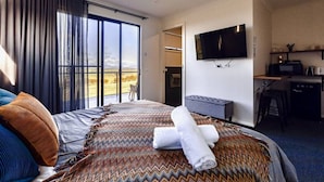 Habitación de hotel con cama, escritorio, televisor y vistas al exterior.
