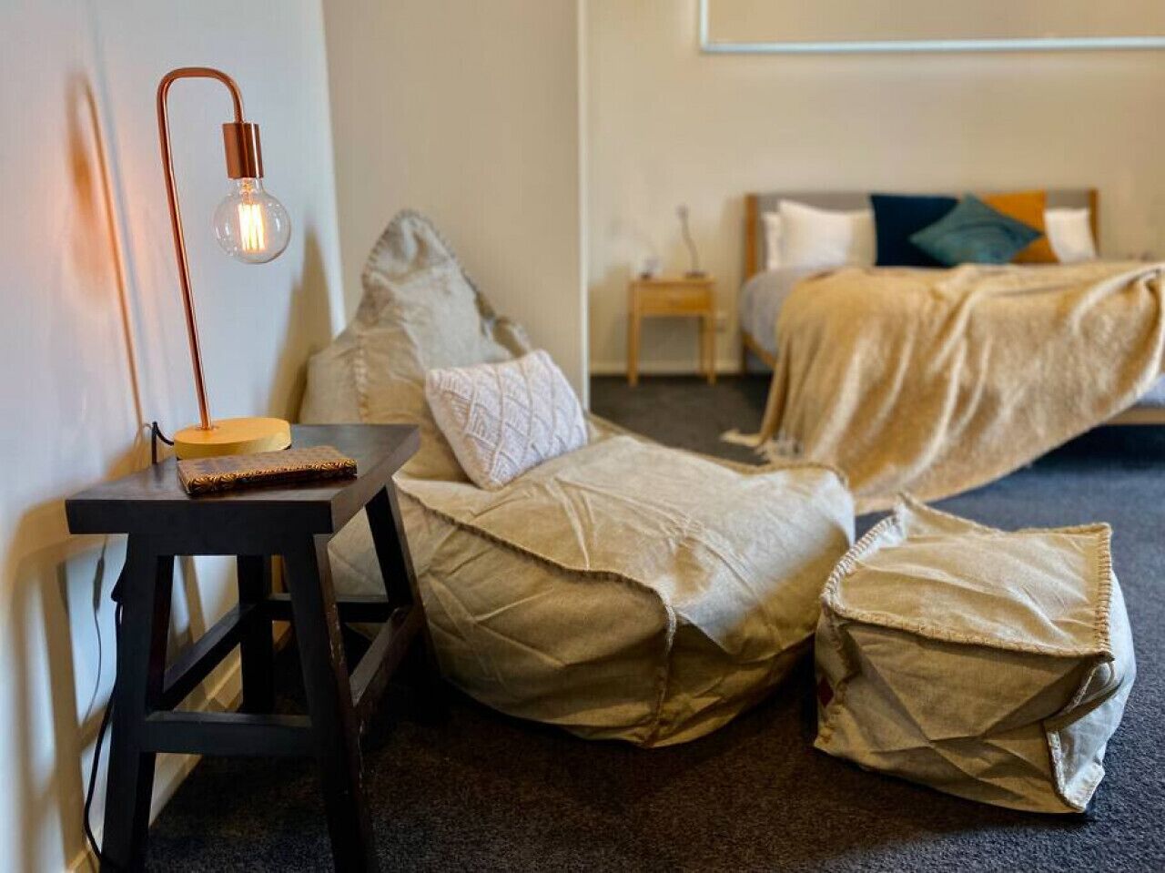 A room with a bed, a small table with a lamp, and a chair.
