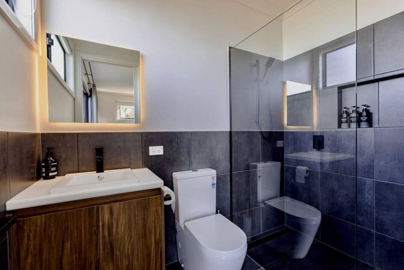 A modern bathroom with a vanity, toilet, and a glass shower enclosure.