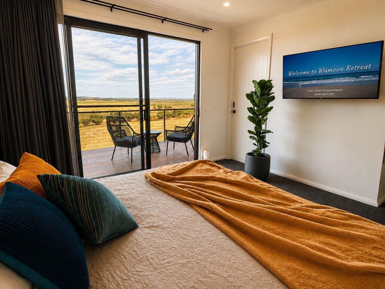 A hotel room with a large bed, a TV on the wall, and a view of the outdoors.