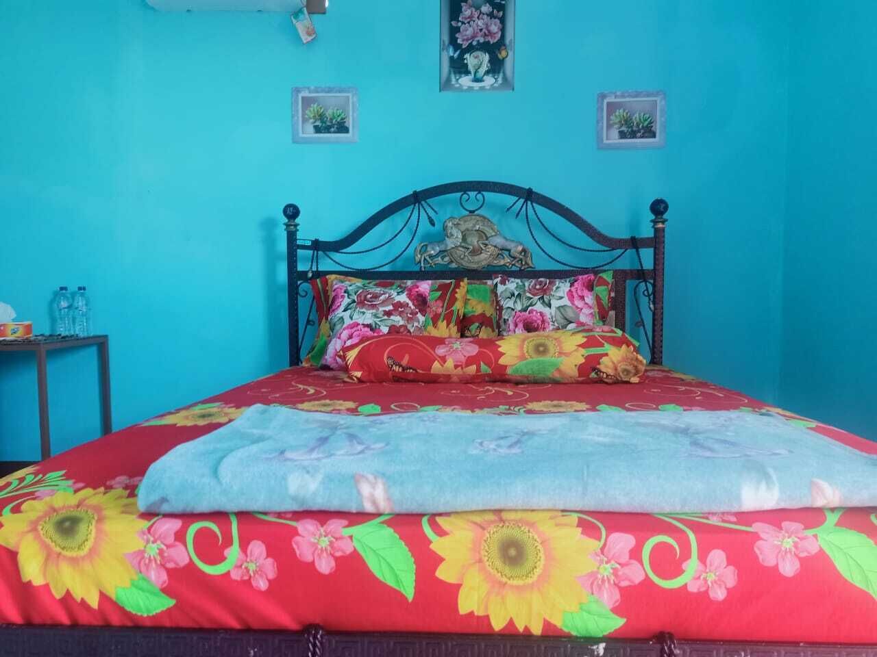 Ein Bett mit blumigem Bettzeug, eine blaue Wand und zwei kleine gerahmte Bilder.