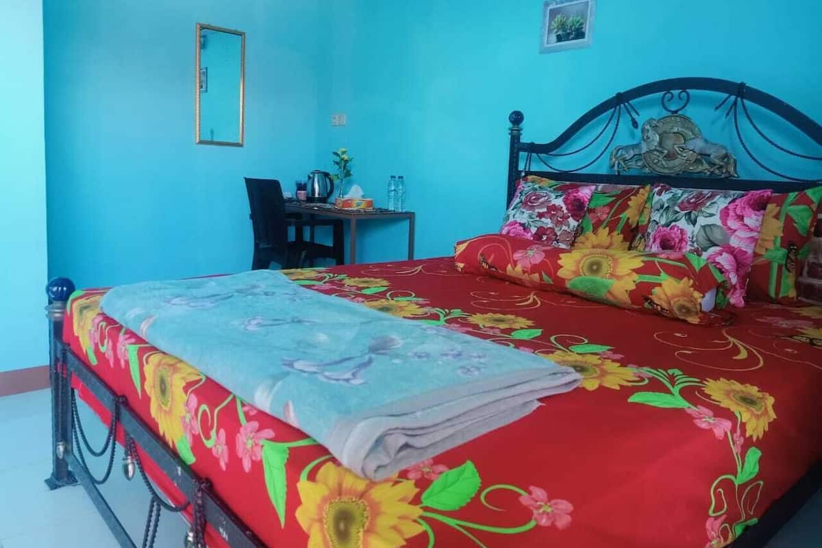 A bedroom with a bed, a desk, and a chair.