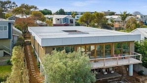 Una casa moderna con techo plano, ventanas grandes y un balcón.