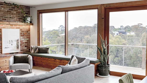 Una sala de estar moderna con un ventanal grande, una pared de ladrillo y vistas al exterior.