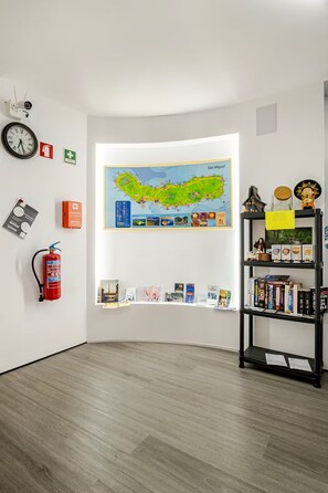 A room with a map, a fire extinguisher, and a bookshelf.