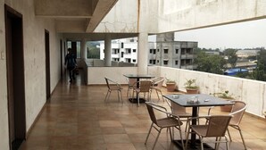 A balcony with tiled flooring, wicker furniture, and potted plants. - Hotel Sumanchandra Suites  (Nashik)