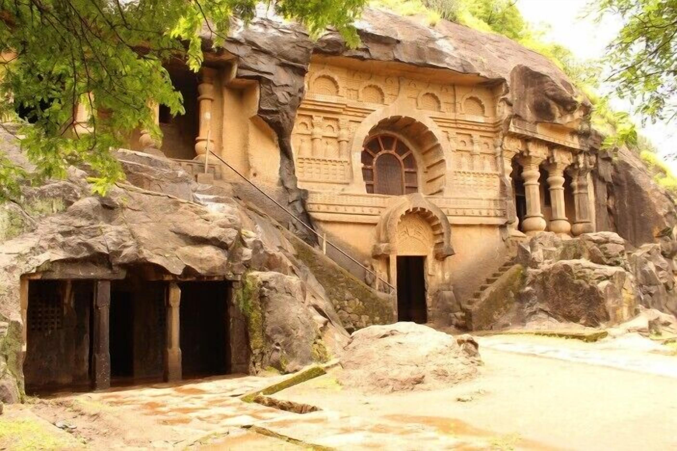 A rock-cut temple with intricate carvings, a staircase leading to the entrance, and a large rock formation.