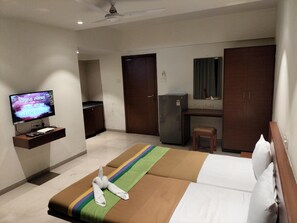 Una habitación de hotel con cama, televisión, escritorio y refrigerador.
