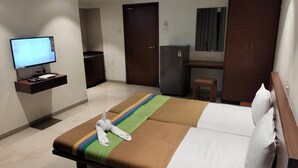 A hotel room with a bed, a desk, a television, and a refrigerator. - Hotel Sumanchandra Suites  (Nashik)