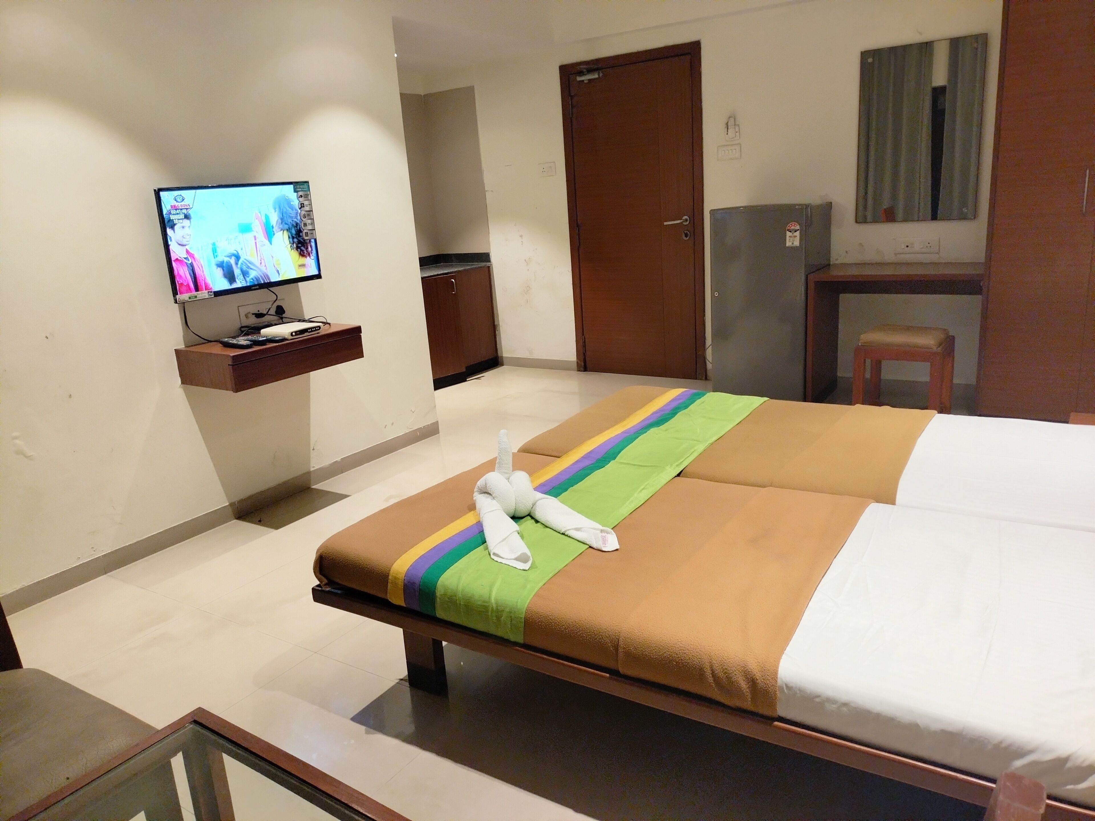 Ein Hotelzimmer mit einem Bett, einem Fernseher auf einem Schrank, einem kleinen Schreibtisch und einem Spiegel.