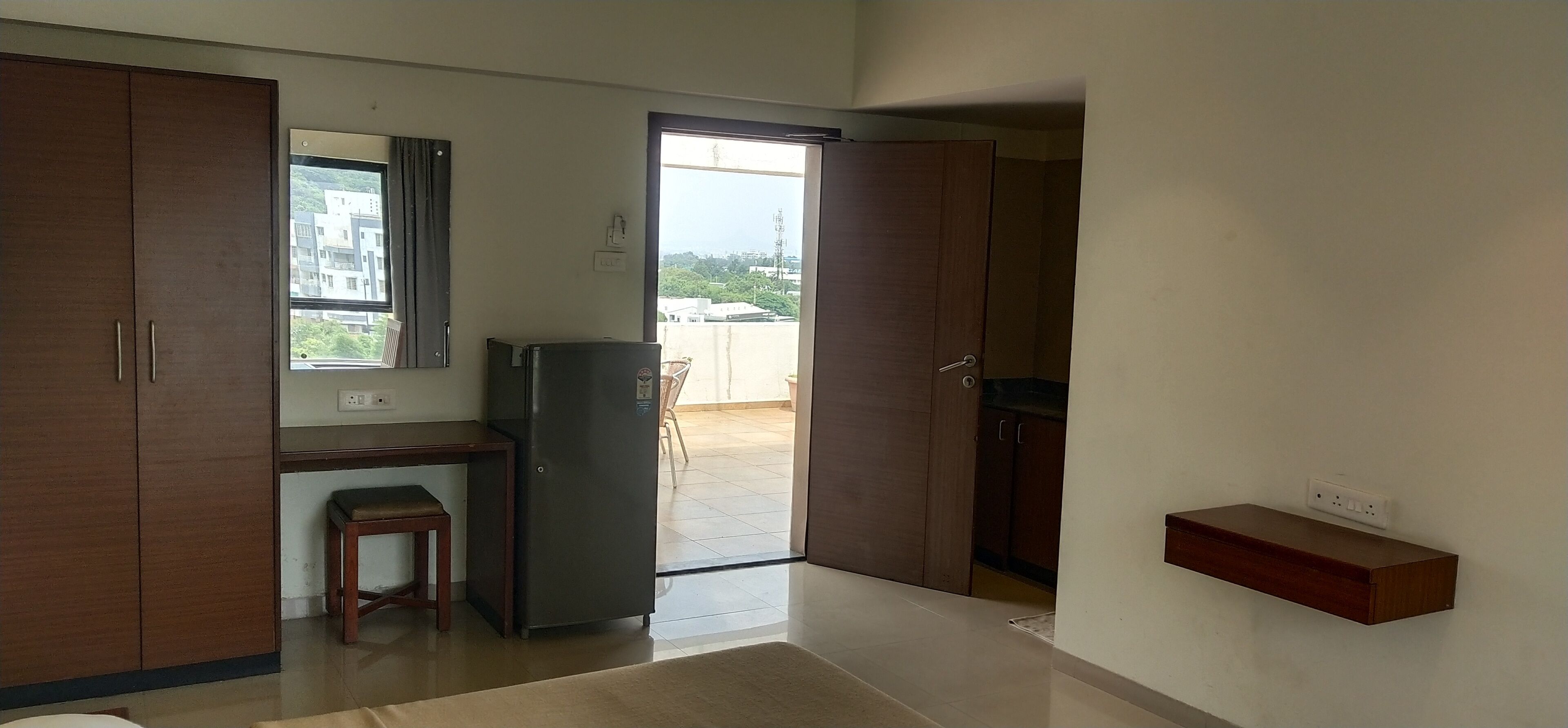 A room with a desk, a chair, a refrigerator, and a wardrobe.