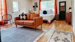 Un dormitorio con una cama, un sofá, un ventilador de techo y una ventana con cortinas.