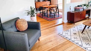 Una sala de estar moderna con un sofá gris, una mesa redonda y piso de madera.