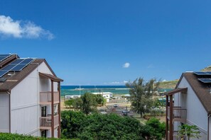 Ein Wohngebiet mit zwei Häusern, jedes mit Solaranlage auf dem Dach, Blick auf das Meer und blauem Himmel.