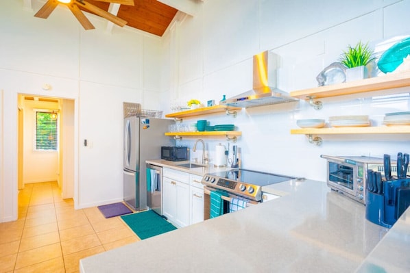 A modern kitchen with stainless steel appliances, wooden shelves, and a view to the outside.