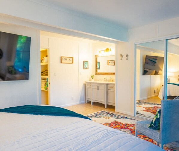 Un dormitorio con cama, cómoda, espejo y armario.