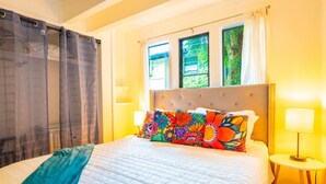 Ein Schlafzimmer mit Bett, Vorhängen, einem Fenster und einer Nachttischlampe.