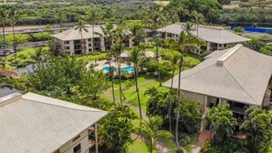 A resort with multiple buildings, a swimming pool, and lush greenery.