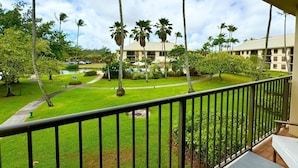 A hotel with a pool, palm trees, and a well-maintained lawn.