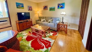 A living room with a sofa, a coffee table, a TV, and artwork on the walls.