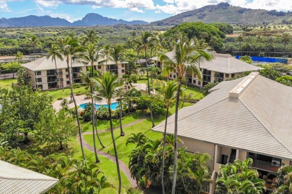 A resort with multiple buildings, a swimming pool, and lush greenery.