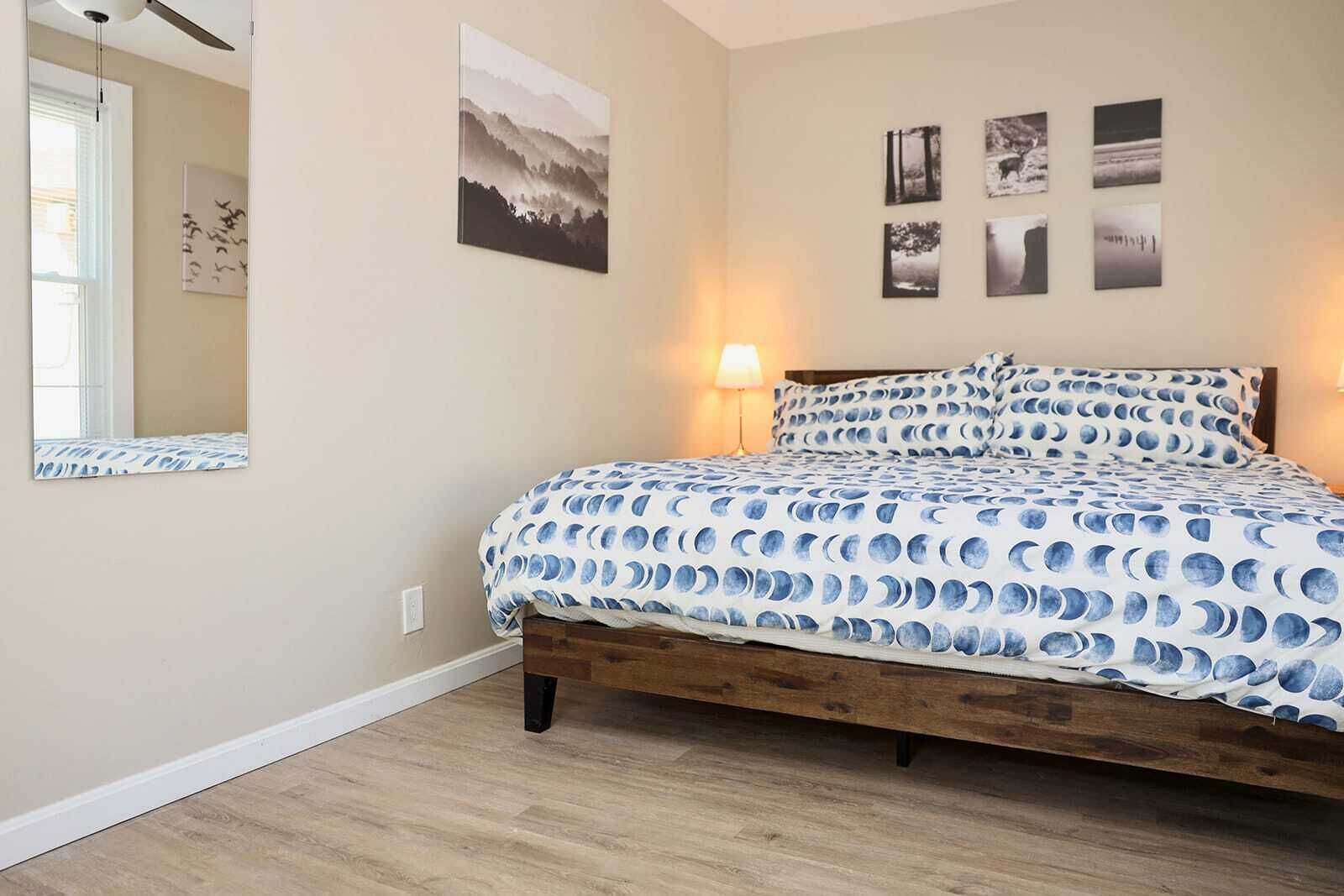 Een slaapkamer met een houten bed, een spiegel en wanddecoratie.
