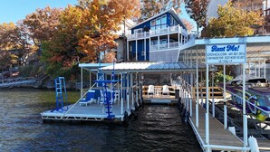 A multi-level dock with a 'Rent Me!' sign, a boat, and a building with a blue exterior. - Luxury Main Channel Lake House, Dock, Party Bar (Rocky Mount)