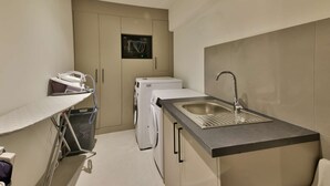 A compact kitchen with a sink, a washing machine, and a drying machine.