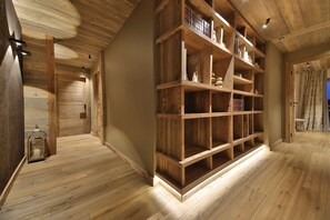 A wooden interior with a bookshelf, a door, and a lamp.