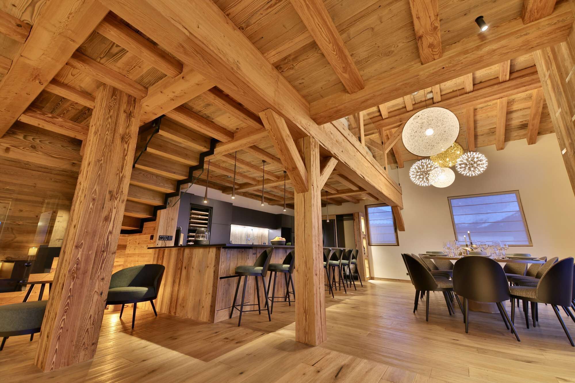 A spacious dining area with wooden beams, a bar, and modern lighting.