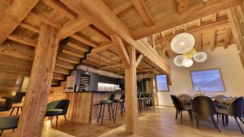 A spacious dining area with wooden beams, a bar, and modern lighting.
