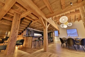 Un amplio comedor con vigas de madera, barra y iluminación moderna.