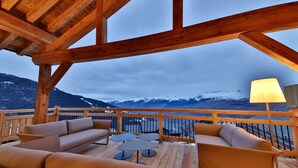 A wooden deck with seating and a view of snow-capped mountains.