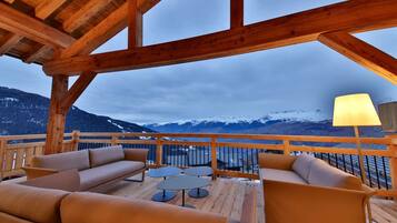 Une terrasse en bois avec des sièges et une vue sur des montagnes enneigées.