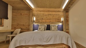 A wooden room with a bed, a chair, and a window.