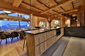 Una cocina moderna con vigas de madera, una isla grande y vistas a un paisaje nevado.