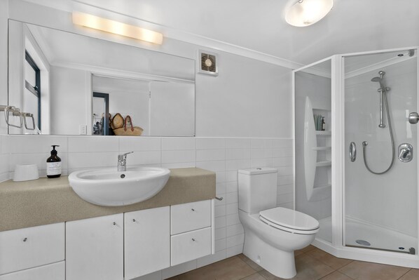 A modern bathroom with a white sink, toilet, and glass-enclosed shower.