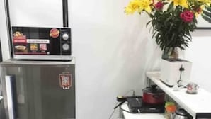 A kitchen with a stainless steel refrigerator, a white tiled backsplash, and a small potted plant with yellow flowers. - Heart of Old Quarter With Balcony View to Street! (ha noi)