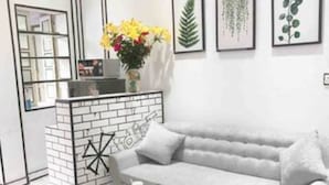 A modern living room with a grey sofa, a small white coffee table, and a brick accent wall. - Heart of Old Quarter With Balcony View to Street! (ha noi)