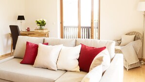 Ein Wohnzimmer mit einer Couch, einem Korbstuhl, einem Holztisch und einer Lampe.