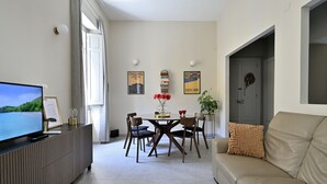 Ein modernes Wohnzimmer mit Flachbildfernseher, einem Esstisch mit Stühlen und einer Couch.