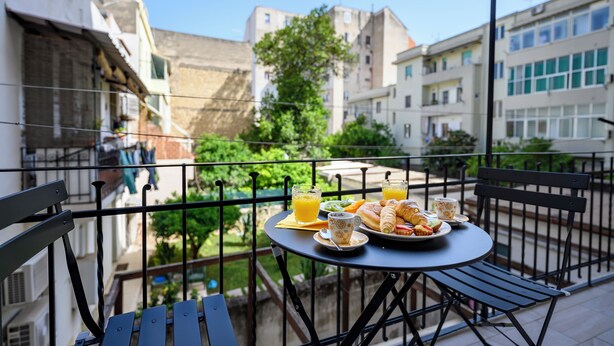 Ein Balkon mit einem Frühstückstisch, gedeckt mit Croissants, Obst und Orangensaft.