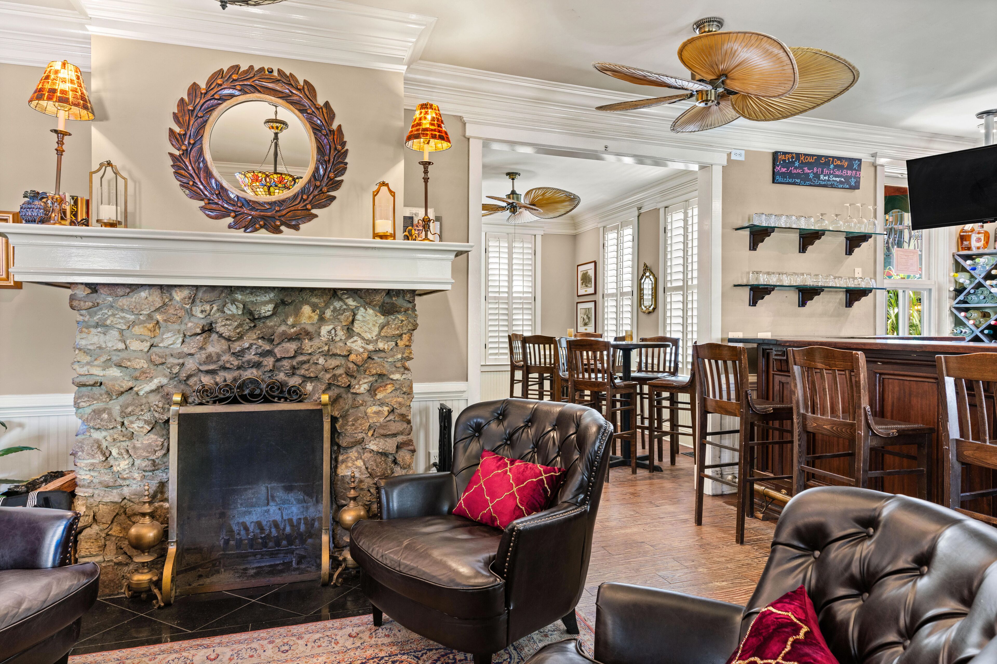 A well-appointed living room with a stone fireplace, leather armchairs, and a dining area with wooden chairs and a bar.