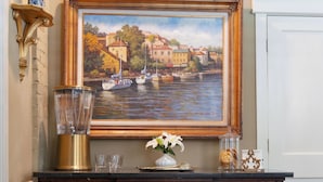 A painting of a riverside town, a vase with flowers, a glass pitcher, and a decorative tray on a wooden dresser. - Village Inn and Pub - Adults Only (St. Simons Island)