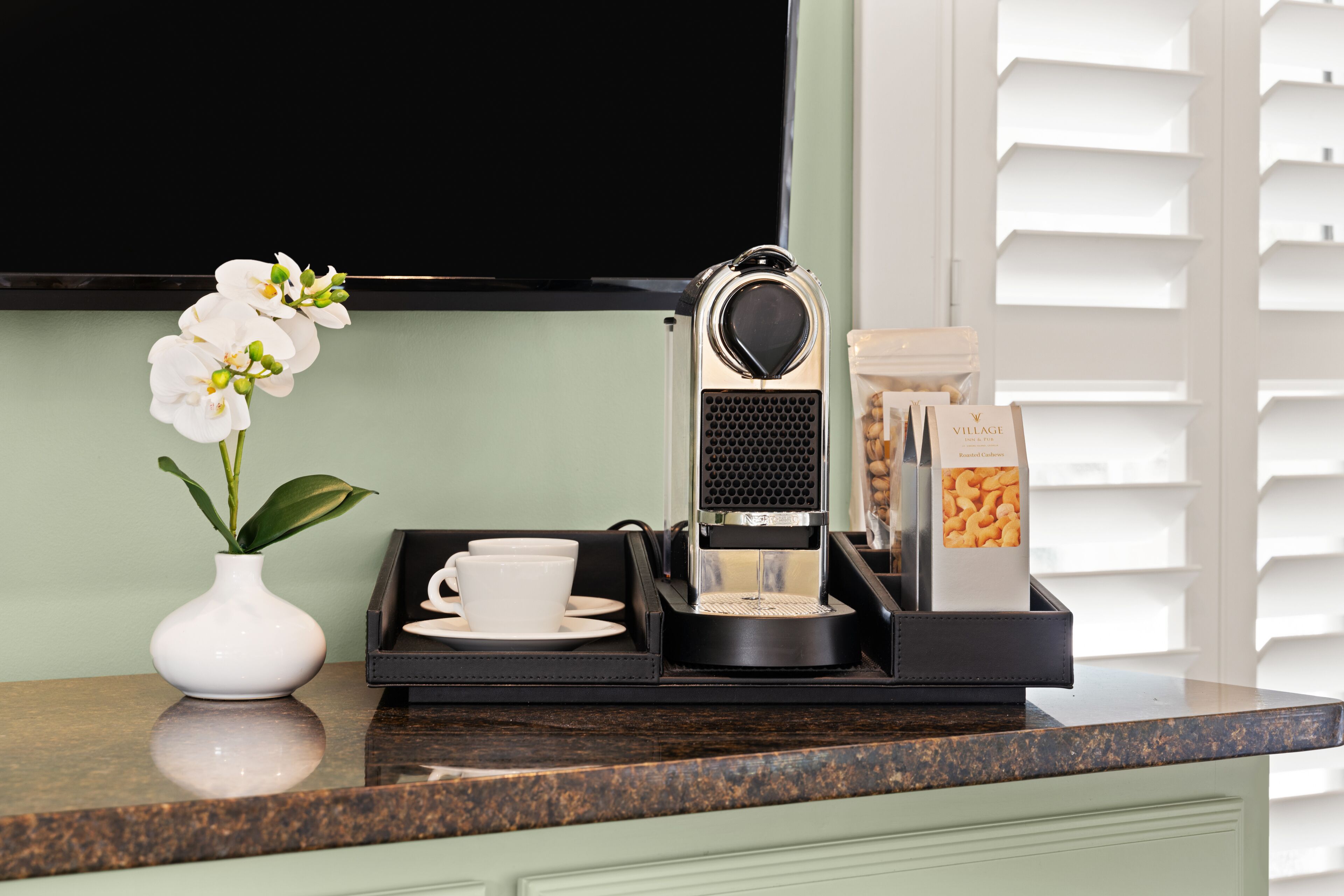 A coffee machine, a cup, a tray, and a box of biscotti on a kitchen counter.
