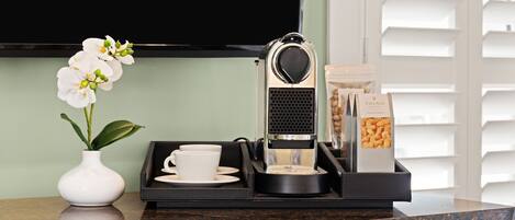 A coffee machine, a cup, a tray, and a box of biscotti on a kitchen counter.